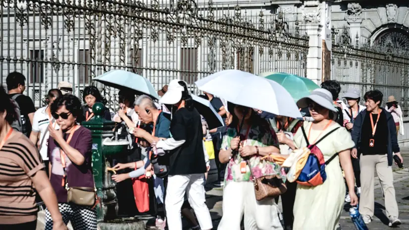 Assalto di turisti giapponesi ad una fontanella in piazza San Giovanni in cerca di refrigerio per combattere le alte temperature dovute all'ondata di caldo estivo. Torino 28 giugno 2025 ANSA/TINO ROMANO