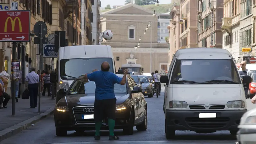 Restare in auto fermi ai semafori della capitale in questi giorni di caldo torrido può essere meno pesante da sopportare se si incappa in qualche intrattenimento improvvisato: Nori G, è un appassionato del calcio e per lui i mondiali non sono mai terminati. Simpatico e paffuto, indossa la maglia della 'Coppa del mondo' con la scritta Italia, e arrotonda la sua giornata palleggiando di testa e con i piedi davanti al semaforo tra via Candia e via Leone IV a Roma. Con il suo spettacolo offre, ai delusi della nostra Nazionale, ancora il piacere di guardare il calcio dai parabrezza delle loro auto. ANSA / LUCIANO DEL CASTILLO/DC/ DBA