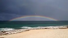 Nuvole scure e un arcobaleno di fronte alla spiaggia di Maimoni nella costa occidentale della Sardegna, Oristano, 24 luglio 2015. ANSA/ALESSANDRO DI MEO