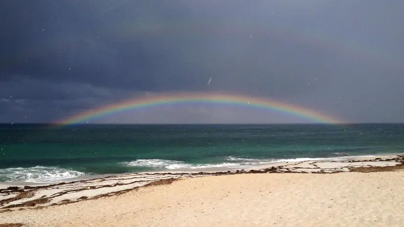 Nuvole scure e un arcobaleno di fronte alla spiaggia di Maimoni nella costa occidentale della Sardegna, Oristano, 24 luglio 2015. ANSA/ALESSANDRO DI MEO
