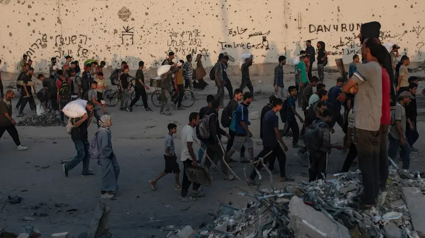epa12181899 Displaced Palestinians carry bags of flour along Rashid Street in western Jabalia, 17 June, 2025, after humanitarian aid trucks entered the northern Gaza Strip through the Israeli-controlled Zikim crossing, northwest of Gaza City. EPA/HAITHAM IMAD