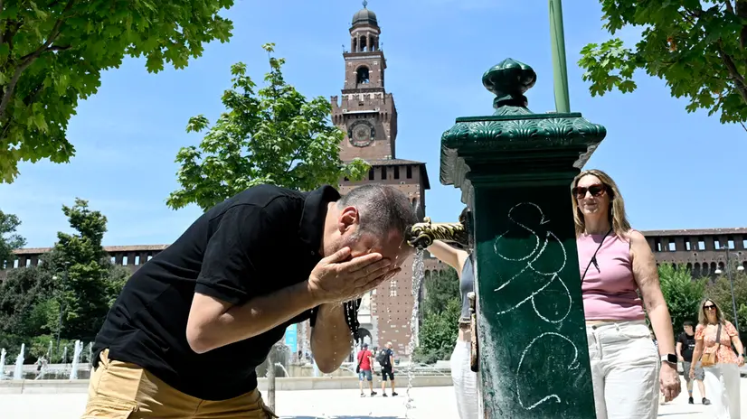 Una persona cerca refrigerio dall'intenso caldo bagandosi il volto con dell'acqua da una fontanella di piazza Castello, Milano, 1 luglio 2025. ANSA/DANIEL DAL ZENNARO