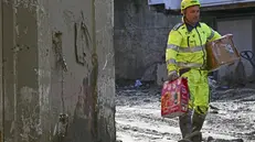 Volontari al lavoro per recuperare dal fango prodotti natalizi esposti in un supermercato inondato dalla frana 4 novembre ANSA/ CIRO FUSCO