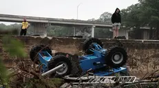 epa12219269 People view a construction vehicle amongst flood debris in the Guadalupe River, in Kerrville, Texas, USA, 05 July 2025. Early 04 July, floodwaters swept through a summer camp and nearby homes, killing at least two dozen people, with dozens of campers still unaccounted for. EPA/DUSTIN SAFRANEK