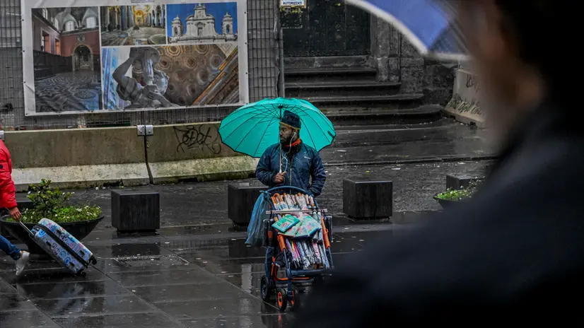 Un venditore di ombrelli in attesa di clienti davanti al duomo di Napoli, 9 marzo 2024 ANSA / CIRO FUSCO