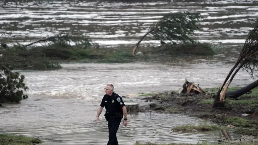 epa12218329 A Kerrville police officer walks along the floodwaters in Kerrville, Texas, USA 05 July 2025. Twenty seven people are confirmed dead and dozens missing after floodwaters swept through a summer camp and nearby homes early 04 July. Search and Rescue teams continue working around the clock following flash flooding on the Guadalupe River in Kerr County. EPA/DUSTIN SAFRANEK