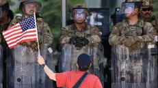 epa12216604 A protester with a US flag stands in front of US Marines guarding the Edward R. Roybal Federal Building, during an Anti-ICE protest held during the Fourth of July holiday, in Los Angeles, California, USA, 04 July 2025. EPA/DAVID SWANSON