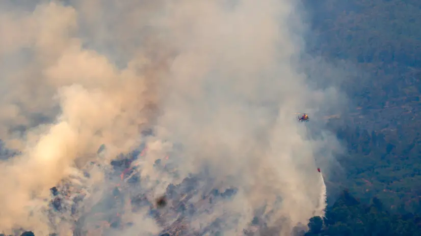 epa12224472 A firefighting helicopter flies during extinguishing works of a forest fire near the town of Pauls, in Tarragona, Spain, 08 July 2025. EPA/QUIQUE GARCIA
