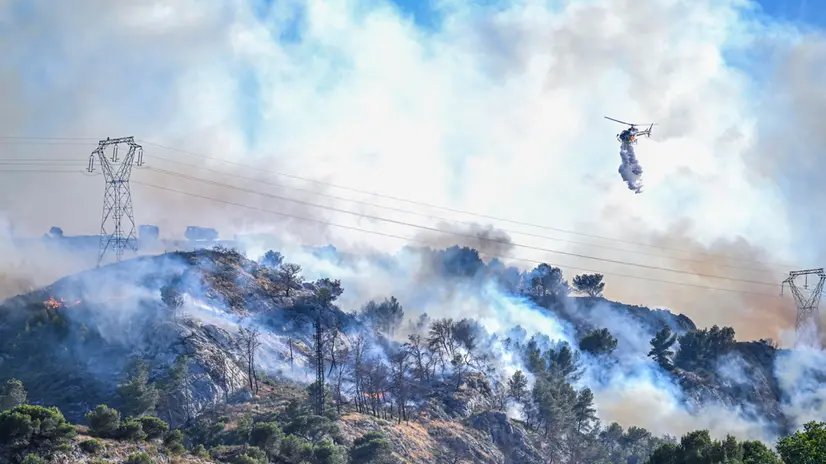 epaselect epa12225403 A helicopter drops water on a wildfire that rapidly expands due to strong winds near the city of Marseille, France, 08 July 2025. Local authorities announced flight suspensions at the airport of Marseille Marignane and started evacuating houses near Les Pennes-Mirabeau. Over 160 firefighters, helicopters and emergency vehicles are fighting the flames fanned by winds up to 70 km/h. EPA/PHILIPPE MAGONI