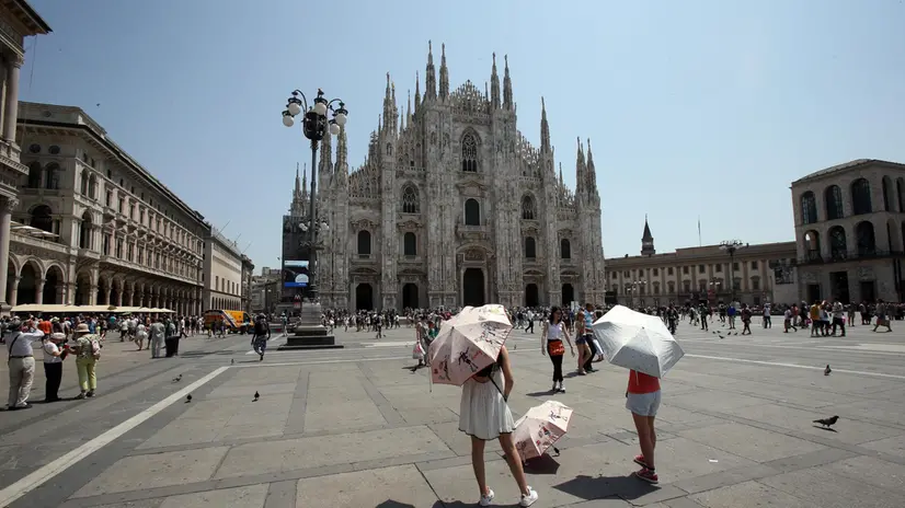 Due turiste si proteggono dal caldo con l'ombrello in piazza del Duomo a Milano. Anche oggi il capoluogo lombardo è stato una della città più calde d'Italia, 6 luglio 2015. MATTEO BAZZI / ANSA