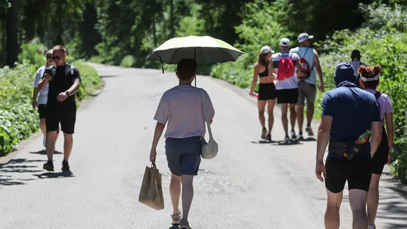 epa12211063 A person shelters from the sun under an umbrella as tourists visit the Morskie Oko lake in the Tatra Mountains, southern Poland, 02 July 2025. A heat wave has arrived in the country, prompting the Institute of Meteorology and Water Management to issue first and second-degree heat warnings nationwide. The second-degree warning applies to northeastern, central, and southwestern Poland. EPA/GRZEGORZ MOMOT POLAND OUT