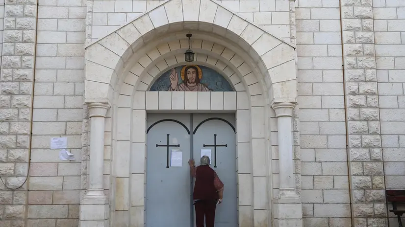 epa11250114 A Palestinian Christian faithful stands outside the Holy Family Church prior to the Good Friday mass in the Al-Zaytoun neighborhood of Gaza City, 29 March 2024. Christians of the Catholic and Western Christian churches around the world on 29 March commemorate Good Friday, the day when, according to the bible, Jesus was crucified by the Romans in Jerusalem. EPA/MOHAMED HAJJAR