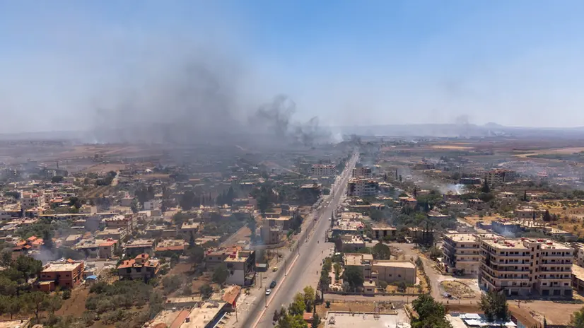 epa12245150 An aerial picture taken by drone shows smoke rising from the town of Al-Mazra'a as a result of burning houses following clashes between Bedouin tribes and local Druze factions, in the Suwayda countryside in southern Syria, on 18 July 2025. Several Bedouin tribes declared a general mobilization to fight against Druze factions after local Druze factions displaced Bedouin families and killed dozens of them. EPA/AHMAD FALLAHA