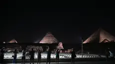 epa11629093 Tourists look at the Giza Pyramids and the Sphinx lit up during the celebration of World Tourism Day, in Giza, Egypt, 27 September 2024. This year's World Tourism Day is observed under the theme 'Tourism and Peace', aiming to highlight its role in fostering peace and understanding between countries and cultures, according to the United Nations. World Tourism Day has been marked annually on 27 September since 1980. EPA/MOHAMED HOSSAM