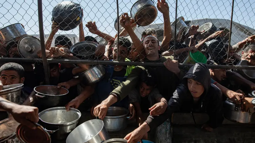 epa12144623 Internally displaced Palestinians gather outside a charity kitchen to receive limited rations amid a shortage of food, in Khan Younis, southern Gaza Strip, 30 May 2025. The United Nations has warned that "the entire population of Gaza is facing the risk of famine" since Israel closed border crossings on 02 March 2025, preventing the entry of essential supplies. The Gaza Government Media Office reported on 24 May that at least 58 people died due to malnutrition, and nearly 250 others due to a lack of food and medicine. EPA/HAITHAM IMAD