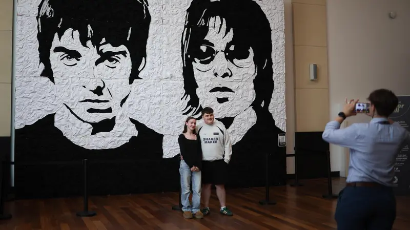 Foto ricordo sotto il murales degli Oasis - Foto Ansa © www.giornaledibrescia.it