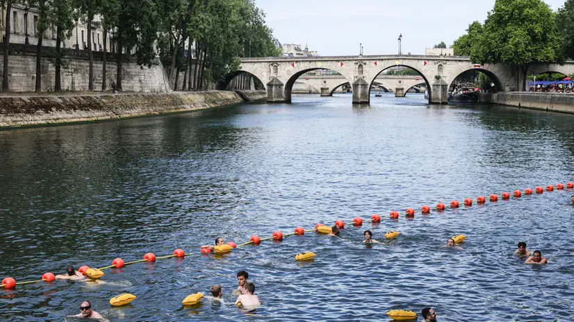 epa12217301 People swim near the Pont Marie, one of the three safe swimming areas that opened to the public on the Seine River, in Paris, France, 05 July 2025. From 05 July to 31 August 2025, people will be able to swim in three safe swimming areas on the Seine river, an activity that has been banned since 1923. EPA/TERESA SUAREZ