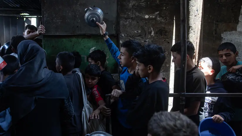 epa12122614 Hundreds of displaced Palestinians gather outside the Sokar Charity Kitchen in Gaza City to receive limited food rations,21 May, 2025. Kitchen officials say their stocks ran out today due to the suspension of humanitarian aid entering the Gaza Strip. EPA/HAITHAM IMAD