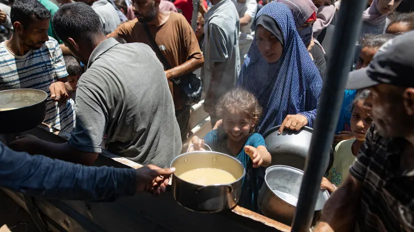 epa12247565 Internally displaced Palestinians gather outside a charity kitchen to receive limited food rations amid the lack of food availability, in Gaza City, 19 July 2025. EPA/HAITHAM IMAD