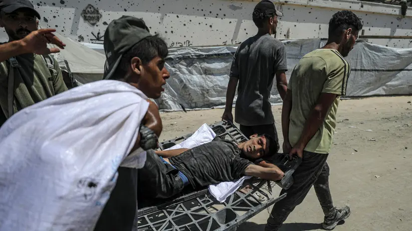 epa12249871 Palestinians use a plastic pallet as a stretcher to carry a man who was wounded during a shooting at a food distribution point near Zikim, northern Gaza Strip, 20 July 2025. According to the Palestinian Ministry of Health in Gaza, at least 67 people were killed while trying to receive humanitarian aid in the Zikim area. EPA/MOHAMMED SABER