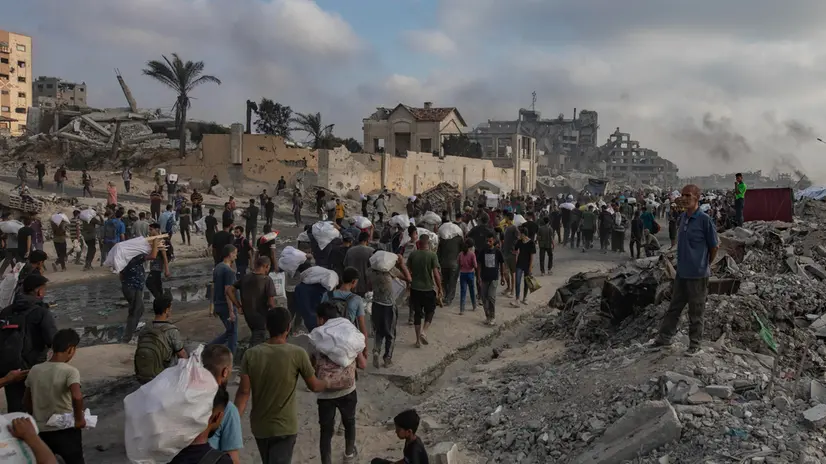 epa12191493 Displaced Palestinians carry relief packages along Rashid Street, west of Jabalia, 22 June 2025, after humanitarian aid trucks entered the northern Gaza Strip through the Israeli-controlled Zikim crossing, northwest of Gaza City. More than 55,700 Palestinians have been killed in the Gaza Strip, according to the Palestinian Ministry of Health, since Israel launched a military campaign in the strip in response to a cross-border attack led by the Palestinian militant group Hamas on 07 October 2023. EPA/HAITHAM IMAD