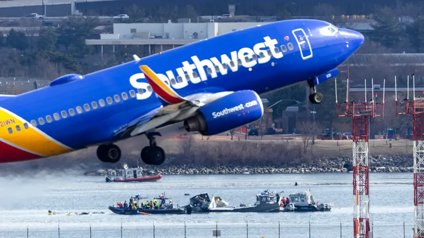 epa11864174 A Southwest Airlines flight takes off from Ronald Reagan Washington National Airport in front of the wreckage of a commercial airplane that collided with a military helicopter, in Arlington, Virginia, USA, 30 January 2025. DC Fire and EMS Chief John Donnelly said no survivors are expected following the collision of an American Eagle Flight, with 60 passengers and four crew members on board, with a US Army Black Hawk helicopter carrying three US service members late on 29 January, over the Potomac River near Reagan Washington National Airport. EPA/JIM LO SCALZO