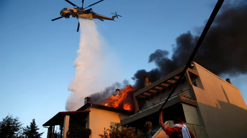 epaselect epa12264285 A firefighting helicopter and volunteers battle to put out a fire burning houses in the residential area of Kryoneri, in the suburbs of Athens, Greece, 26 July 2025. Firefighting forces are battling the wildfire that broke out in Kryoneri, Attica. According to the Fire Service, the fire is considered difficult as it is spreading through a mixed area of forest and residential zones. There are reports of damage to homes, and some have been engulfed in flames. EPA/YANNIS KOLESIDIS