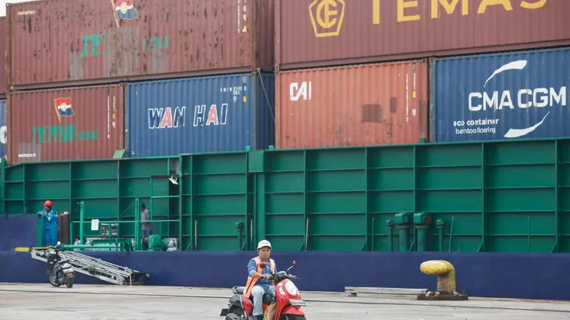 epa12240800 A worker rides a motorbike near container ships at the Tanjung Priok port which is operated by the Indonesian state-owned PT Pelindo, in Jakarta, Indonesia, 16 July 2025. US government has reached a trade deal with Indonesia to lower the tariffs on Indonesian goods to 19 percent from previous 32 percent, following negotiations, according to Indonesian President Prabowo. EPA/BAGUS INDAHONO