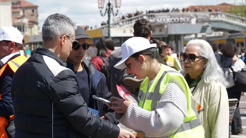 Un’operatrice ai varchi controlla il ticket di accesso sul telefonino di un turista, al check point del piazzale della stazione ferroviaria, Venezia 25 aprile 2024. ANSA/ANDREA MEROLA