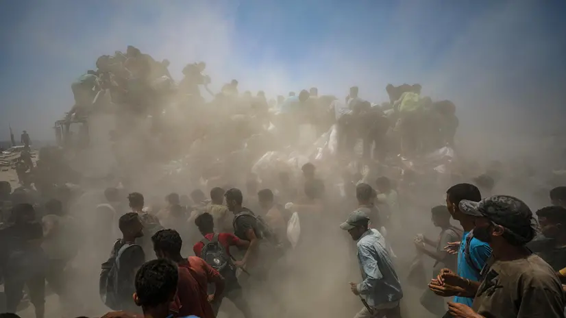 epa12265780 Internally displaced Palestinians try to grab bags of flour from an aid truck near a food distribution point in Zikim, northern Gaza Strip, 27 July 2025. The Israeli army declared a 'tactical pause' in military operations in parts of the Gaza Strip on 27 July, to facilitate the safe passage of humanitarian aid convoys. More than 130 Palestinians, the majority of whom children, have died of malnutrition in the Gaza Strip, the Palestinian Ministry of Health said on 27 July. EPA/MOHAMMED SABER