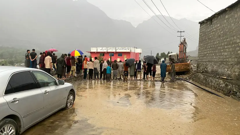 epa12271212 People stand next to a waterlogged road following floods that affected Sakwar village, in Gilgit-Baltistan, Pakistan, 29 July 2025. Rescuers and military helicopters have airlifted more than 130 people from flood-hit zones across Gilgit-Baltistan, where at least nine people have died and over 500 homes and vital infrastructure were damaged. EPA/MERAJ ALAM