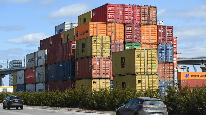 epa12010063 Cars pass shipping containers at a Ray-Mont Logistics transload facility Montreal, Canada, 04 April 2025. Canadian Prime Minister Mark Carney announced this week a 25 percent tariff on vehicles made in the United States in response to new tariffs that were announced by US President Donald Trump. EPA/GRAHAM HUGHES