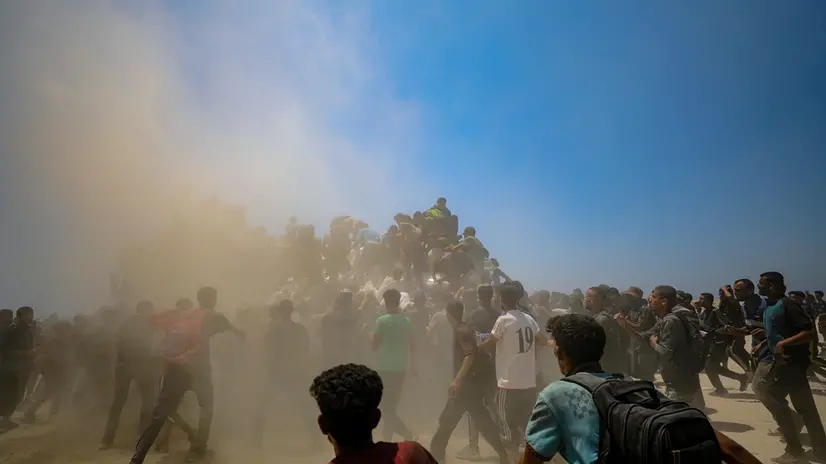 epa12265801 Internally displaced Palestinians try to grab bags of flour from an aid truck near a food distribution point in Zikim, northern Gaza Strip, 27 July 2025. The Israeli army declared a 'tactical pause' in military operations in parts of the Gaza Strip on 27 July, to facilitate the safe passage of humanitarian aid convoys. More than 130 Palestinians, the majority of whom children, have died of malnutrition in the Gaza Strip, the Palestinian Ministry of Health said on 27 July. EPA/MOHAMMED SABER