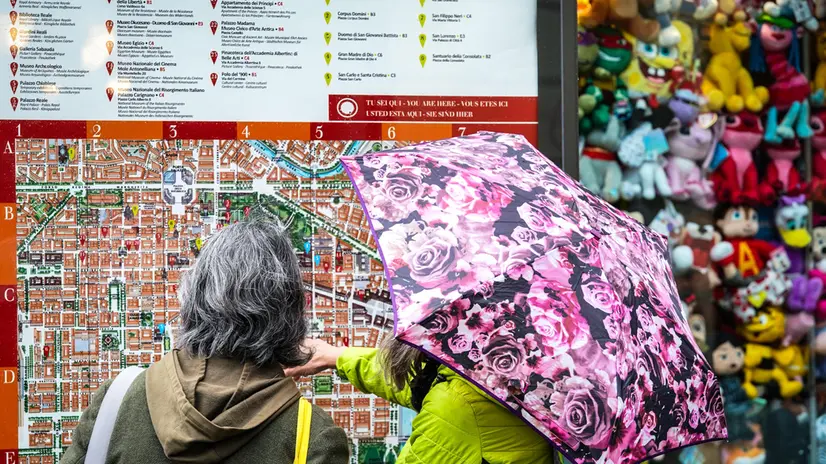 Maltempo, due turiste consultano una mappa della città sotto la pioggia. Torino 14 aprile 2025 ANSA/TINO ROMANO