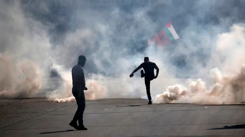 epaselect epaselect epa10917338 A Palestinian man kicks away a tear gas canister during clashes with Israeli forces in the West Bank city of Nablus, 13 October 2023. According to the Palestinian Ministry of Health, 11 people were killed in the West Bank towns on 13 October. More than 1,700 Palestinians have been killed in the Gaza Strip and over 7,300 others injured, according to the Palestinian Ministry of Health, after Israel started bombing the Palestinian enclave in response to attacks carried out by the Islamist movement Hamas on Israel from the Gaza Strip on 07 October. EPA/ALAA BADARNEH