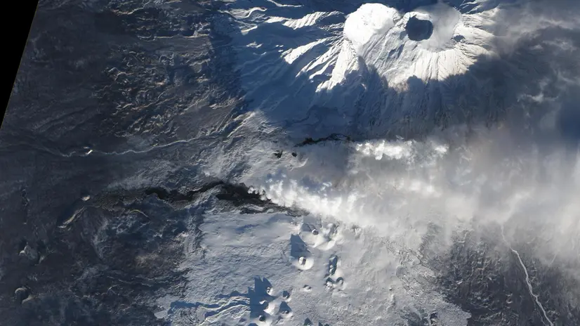 After more than a month of eruption, lava continues to flow from Tolbachik, one of many active volcanoes on Russias Kamchatka Peninsula. The current eruption at Tolbachik began on November 27, 2012. Lava flowed up to 20 kilometers (12 miles) from a line of fissures on the volcanos southern flank. Since then, some of the lava has cooled enough to allow snow to accumulate. Snow-covered lava flows appear gray in this natural-color satellite image. Fresher lava appears black. A faint orange glow at the head of the northern flow marks the location of an erupting fissure. The image was collected on December 22, 2012, by the Advanced Land Imager (ALI) on the Earth Observing-1 (EO-1) Satellite. According to the Kamchatka Volcanic Eruption Response Team (KVERT) the eruption continued through December 30, 2012. NASA Earth Observatory image by Jesse Allen and Robert Simmon, using EO-1 ALI data from the NASA EO-1 teamand the USGS Global Visualization Viewer. Caption by Robert Simmon. ANSA / NASA +++NO SALES - EDITORIAL USE ONLY+++