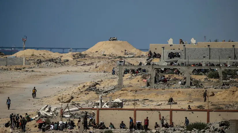 epa12249923 Palestinians take cover as an Israeli tank guards an aid distribution point near Zikim, northern Gaza Strip, 20 July 2025. According to the Palestinian Ministry of Health in Gaza, at least 67 people were killed while trying to receive humanitarian aid in the Zikim area. EPA/MOHAMMED SABER