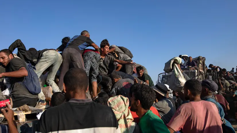 epa12283318 Internally displaced Palestinians climb aid trucks to get food near a food distribution point in the Morag corridor, south of Khan Younis, in the southern Gaza Strip, 04 August 2025. EPA/HAITHAM IMAD