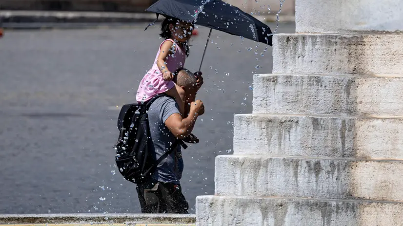 Una bambina sulle spalle del papà si proteggono dal sole con un ombrello a piazza del Popolo. Roma, 27 luglio 2024 ANSA/MASSIMO PERCOSSI
