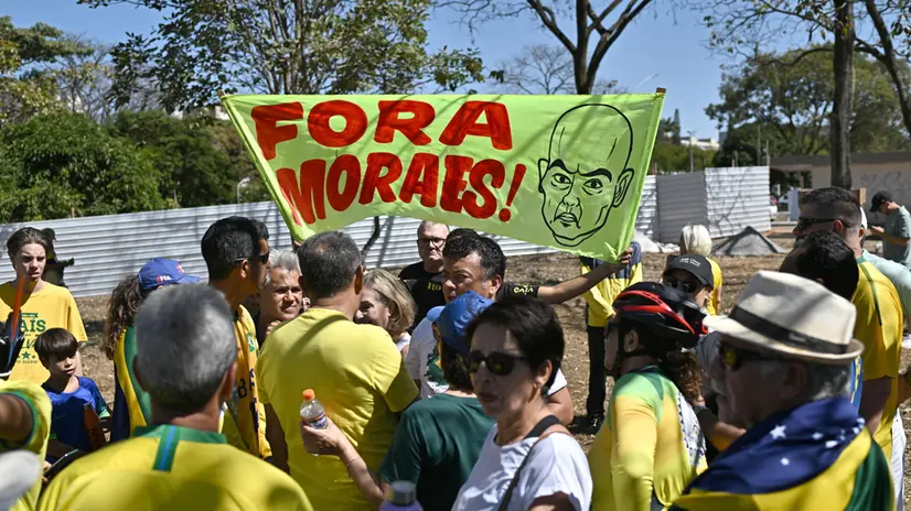 epa12249903 A man holds a sign reading 'Out with Moraes', referring to Brazilian Supreme Court Justice Alexandre de Moraes, during a protest in support of former Brazilian President Jair Bolsonaro in front of the Central Bank in Brasilia, Brazil, 20 July 2025. EPA/ANDRE BORGES