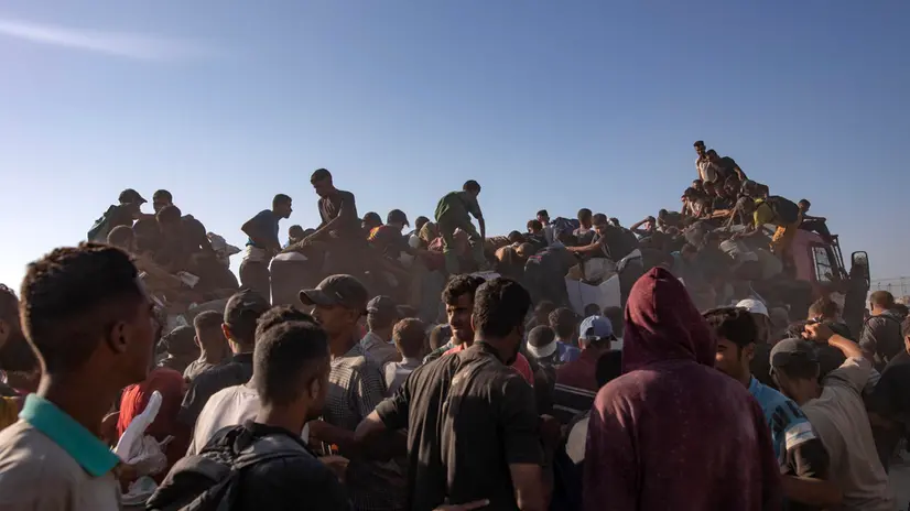 epa12283326 Internally displaced Palestinians climb aid trucks to get food near a food distribution point in the Morag corridor, south of Khan Younis, in the southern Gaza Strip, 04 August 2025. EPA/HAITHAM IMAD