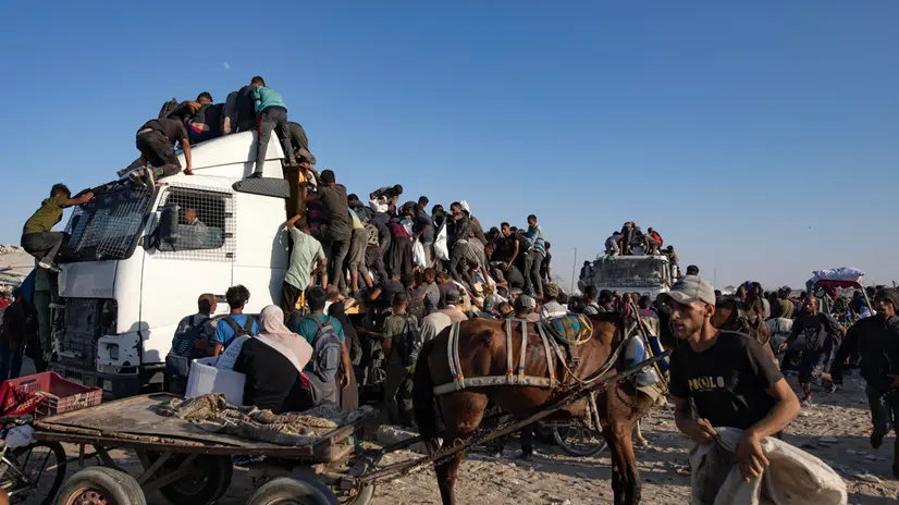 epa12283320 Internally displaced Palestinians climb aid trucks to get food near a food distribution point in the Morag corridor, south of Khan Younis, in the southern Gaza Strip, 04 August 2025. EPA/HAITHAM IMAD