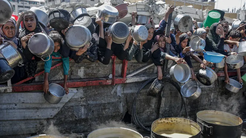epa12282741 Internally displaced Palestinians, including children, hold pots as they gather to receive food from a charity kitchen, in Gaza City, Gaza Strip, 04 August 2025. Humanitarian organizations have warned of an imminent food catastrophe for thousands of children, a crisis caused by severe food insecurity, a decline in health services, and ongoing restrictions on humanitarian aid and essential supplies. EPA/MOHAMMED SABER