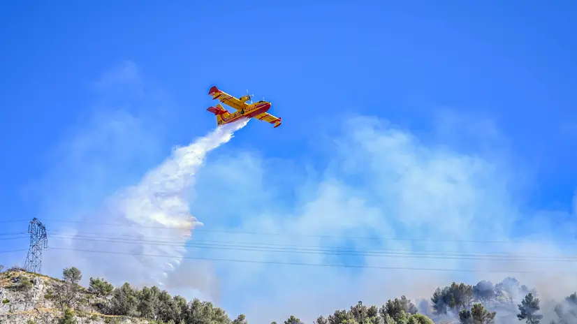 epa12225402 A plane drops water on a wildfire that rapidly expands due to strong winds near the city of Marseille, France, 08 July 2025. Local authorities announced flight suspensions at the airport of Marseille Marignane and started evacuating houses near Les Pennes-Mirabeau. Over 160 firefighters, helicopters and emergency vehicles are fighting the flames fanned by winds up to 70 km/h. EPA/PHILIPPE MAGONI