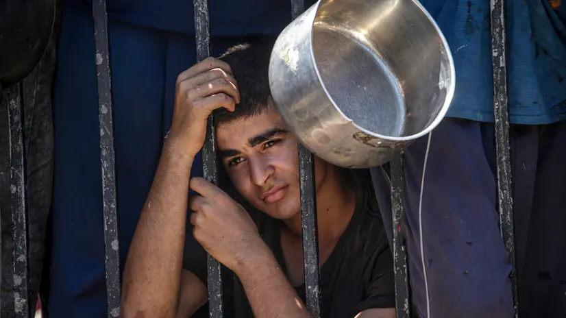 epa12282762 An internally displaced Palestinian youth gathers to receive food from a charity kitchen, in Gaza City, Gaza Strip, 04 August 2025. Humanitarian organizations have warned of an imminent food catastrophe for thousands of children, a crisis caused by severe food insecurity, a decline in health services, and ongoing restrictions on humanitarian aid and essential supplies. EPA/MOHAMMED SABER