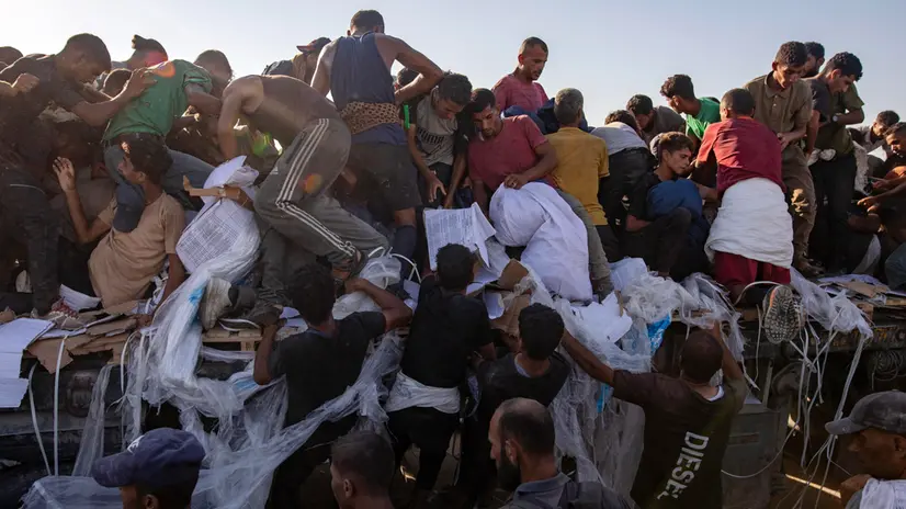 epa12283317 Internally displaced Palestinians climb aid trucks to get food near a food distribution point in the Morag corridor, south of Khan Younis, in the southern Gaza Strip, 04 August 2025. EPA/HAITHAM IMAD