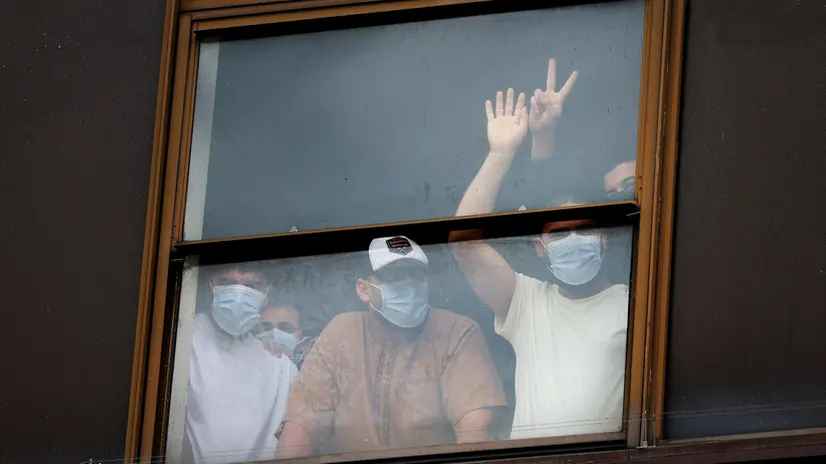 epa12279707 Migrants look out a window from a hotel during a demonstration against the far-right outside a hotel housing asylum seekers in London, Britain, 02 August 2025. Far-right protests outside hotels housing migrants have been increasing across the UK in recent weeks, with counter-protests also taking place. EPA/ANDY RAIN