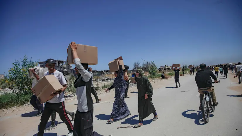epa12143218 Palestinians carry aid supplies received from the US-backed Gaza Humanitarian Foundation through an area known as the Netzarim Corridor, central Gaza Strip, 29 May 2025. According to the UN half a million people, or one in five people in the Strip are facing starvation while the entire population of the Gaza Strip continues to face a critical risk of famine following 19 months of conflict, mass displacement and severe restrictions on humanitarian aid. EPA/HAITHAM IMAD