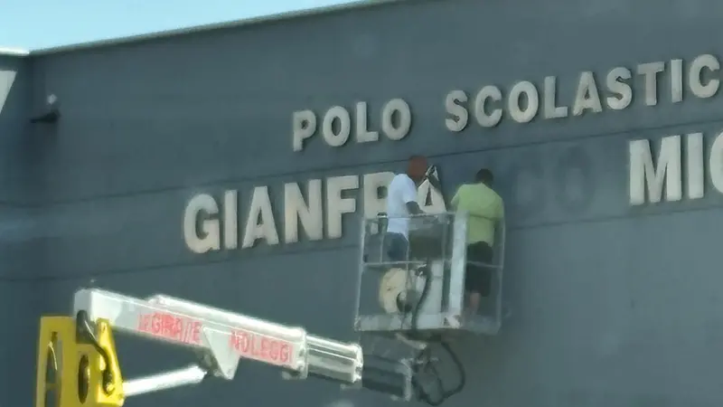 Gli operai rimuovono la scritta dalla scuola di Adro - © www.giornaledibrescia.it