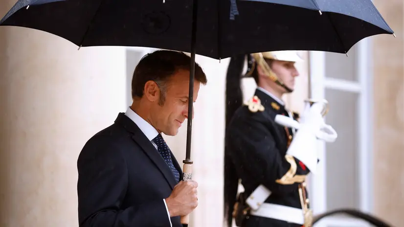 epa12258536 French President Emmanuel Macron holds an umbrella as he awaits the Lebanese Prime Minister Nawaf Salam (not pictured) upon his arrival at the Elysee Palace in Paris, France, 24 July 2025. This marks the first official visit of the Lebanese prime minister to France, with the purpose to reaffirm the diplomatic relationship between the two countries. EPA/YOAN VALAT
